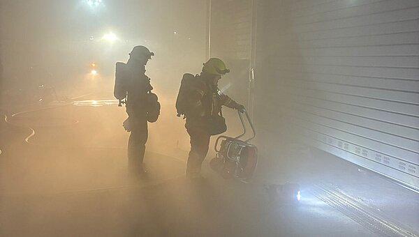 Two firefighters in front of the smoke-filled garage