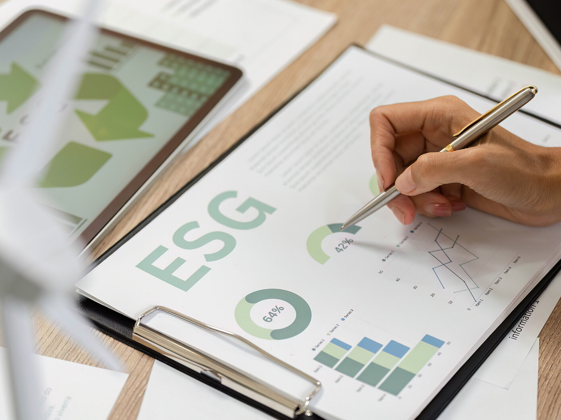 Hand mit einem Stift, die ein Datenblatt zum Thema "ESG" bearbeitet.