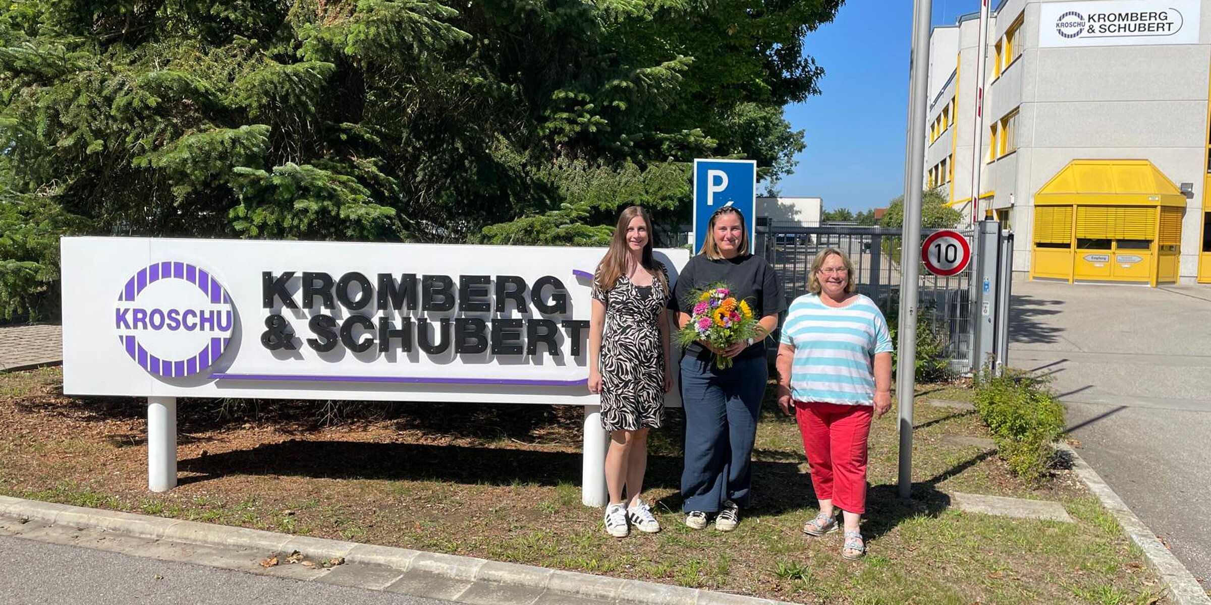 New JAV chairwoman with a bouquet of flowers and representatives from HR and the works council in front of the company premises.