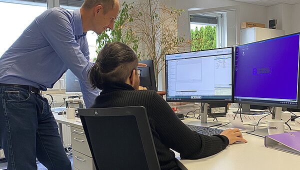 Kroschu supervisor shows the BBW intern something on the screen.