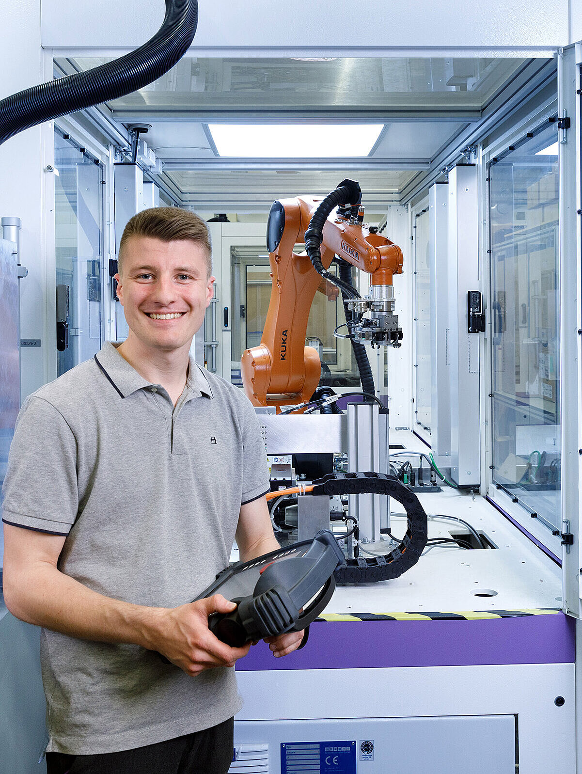 Mitarbeitender aus der Entwicklung vor einem Roboter-Greifarm.