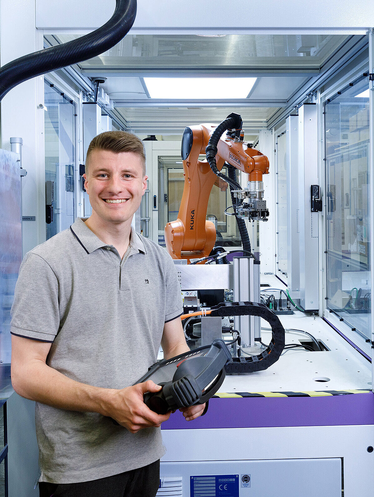 Mitarbeitender aus der Entwicklung vor einem Roboter-Greifarm.
