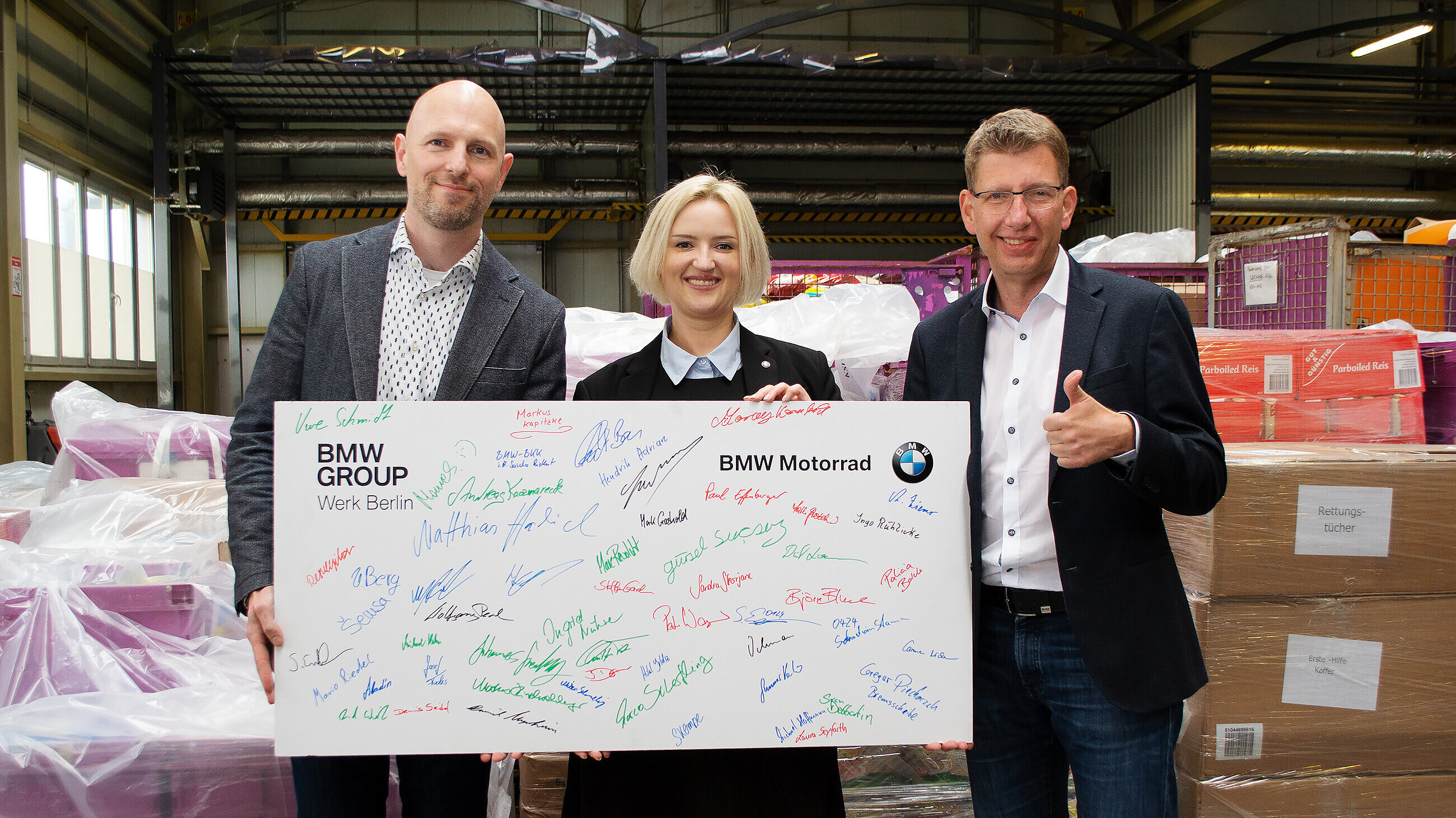 Werksleitung Ukraine mit einem Geschäftsführer und einer unterschriebenen Karte von unserem Kunden BMW vor Hilfsgütern.