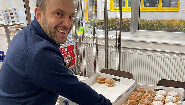 A smiling employee, who enjoys a donut.