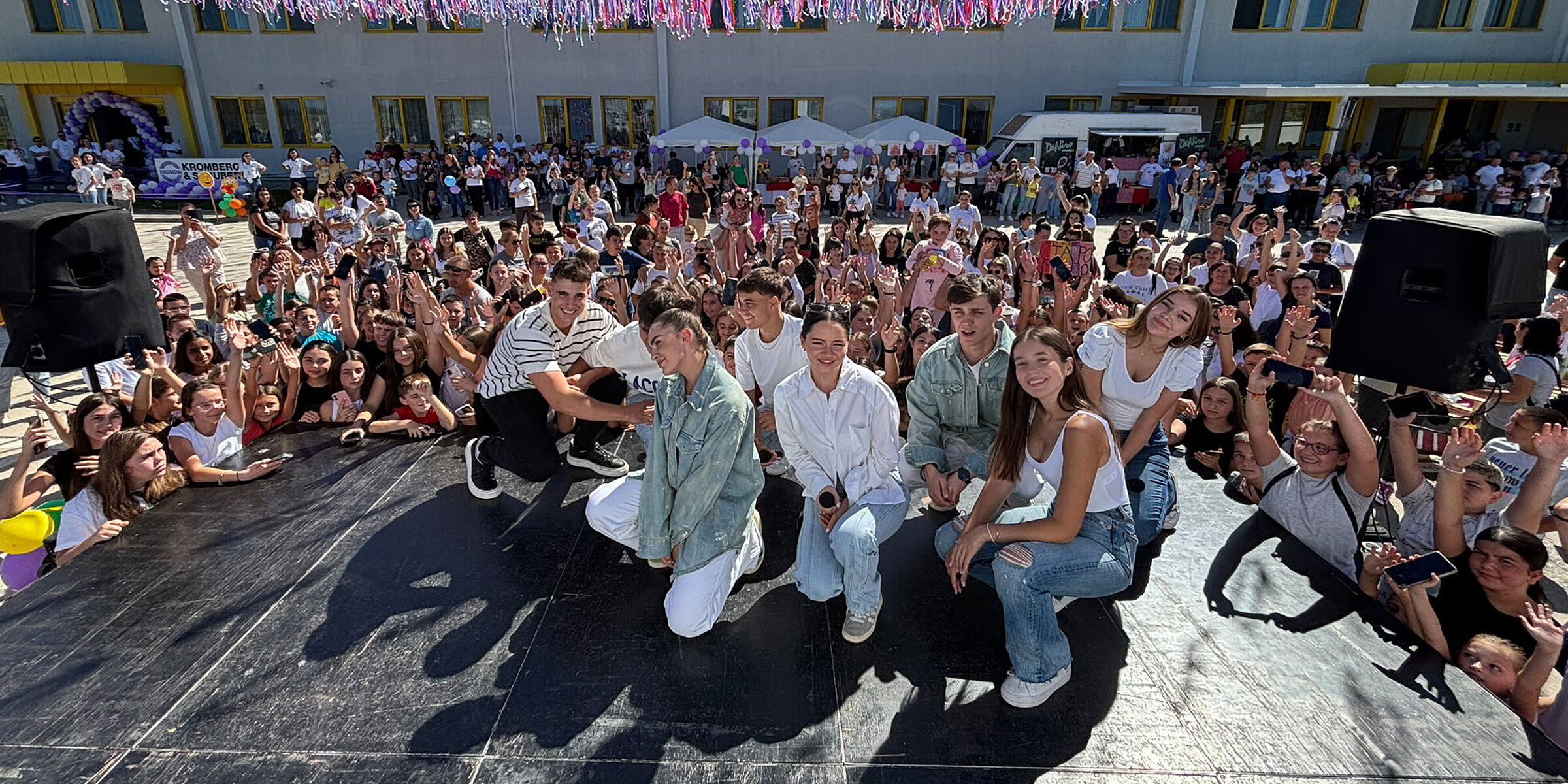 Band performing on stage with children celebrating in the background at the Children's Festival