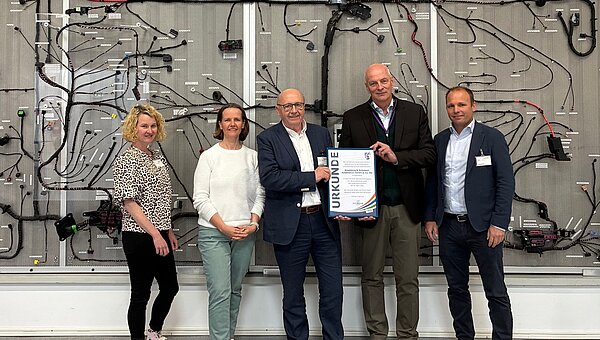 District Administrator Martin Neumeyer with Kroschu Managing Director presenting a certificate in front of a wiring harness.