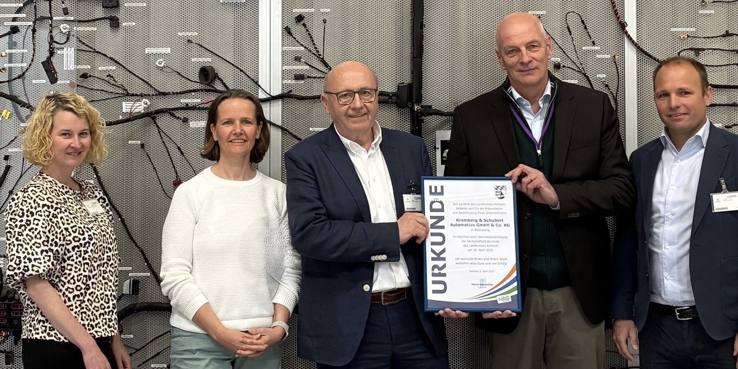 District Administrator Martin Neumeyer with Kroschu Managing Director presenting a certificate in front of a wiring harness.