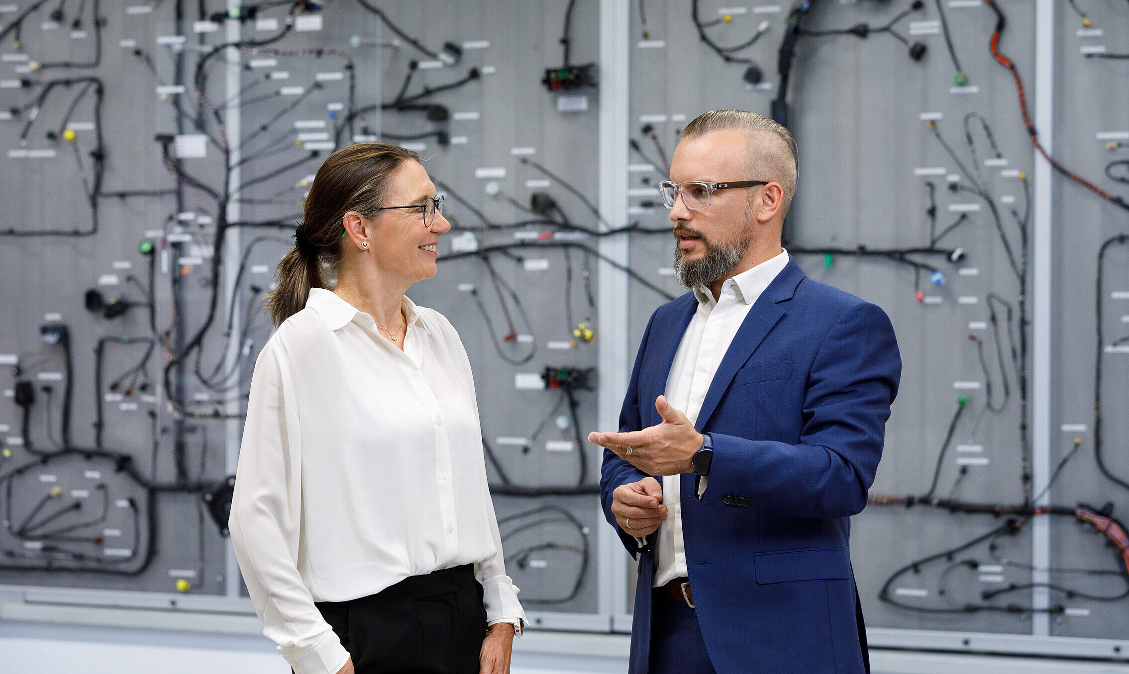 Gesprächssituation zwischen zwei Personen vor einem Bordnetz.
