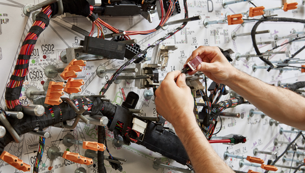 Two hands working on a cable board for an wiring harness system.