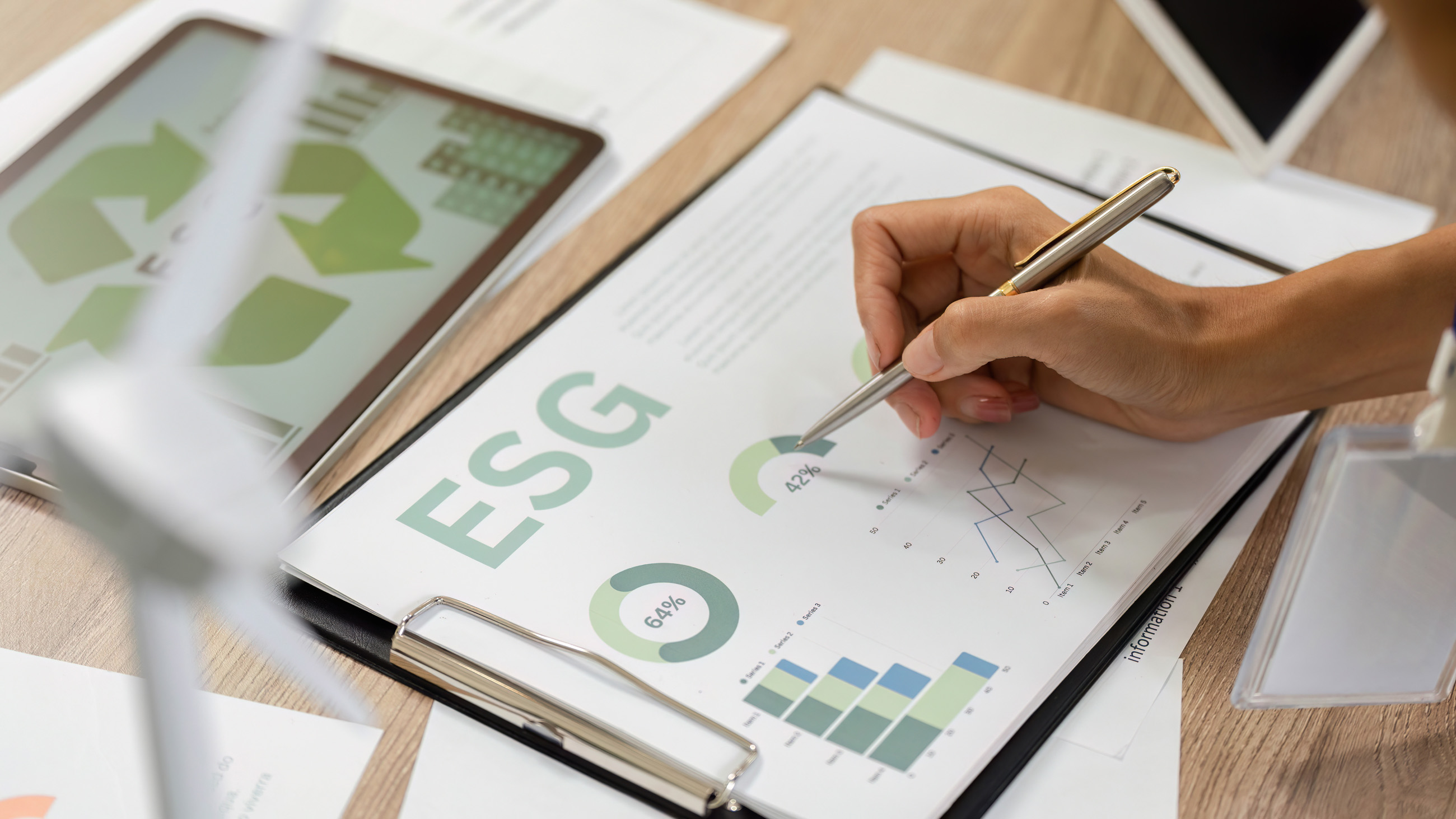 Hand mit einem Stift, die ein Datenblatt zum Thema "ESG" bearbeitet.