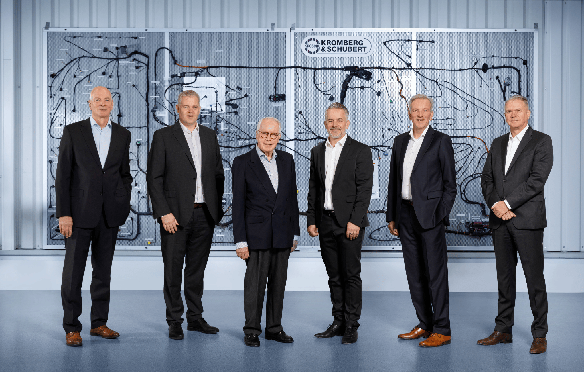 Management Team in front of a wiring harness